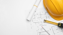 Image of blueprints with a ruler and hard hat sitting on top of them