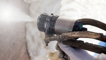 Close up of spray foam gun spraying foam
