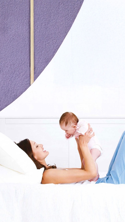 Mom and baby playing with an  wall revealing WALLTITE spray foam insulation in the background. 