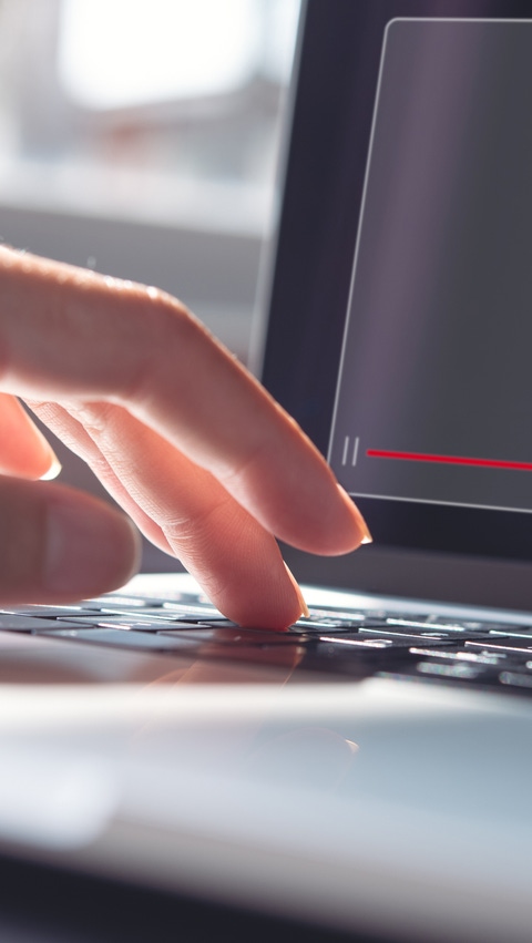 Image of a hand typing on a laptop keyboard