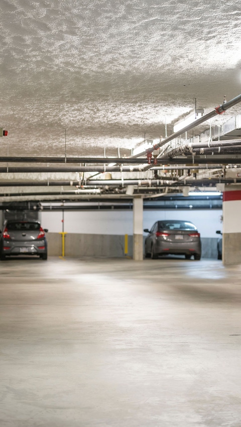 A parking garage with spray foam insulation covered with a cementitious finish as the overhead