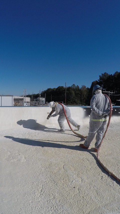 Image of installers on flat roof installing spray roof system