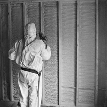 A black and white image of a spray foam contractor installing closed-cell spray polyurethane foam cropped in a sqaure format